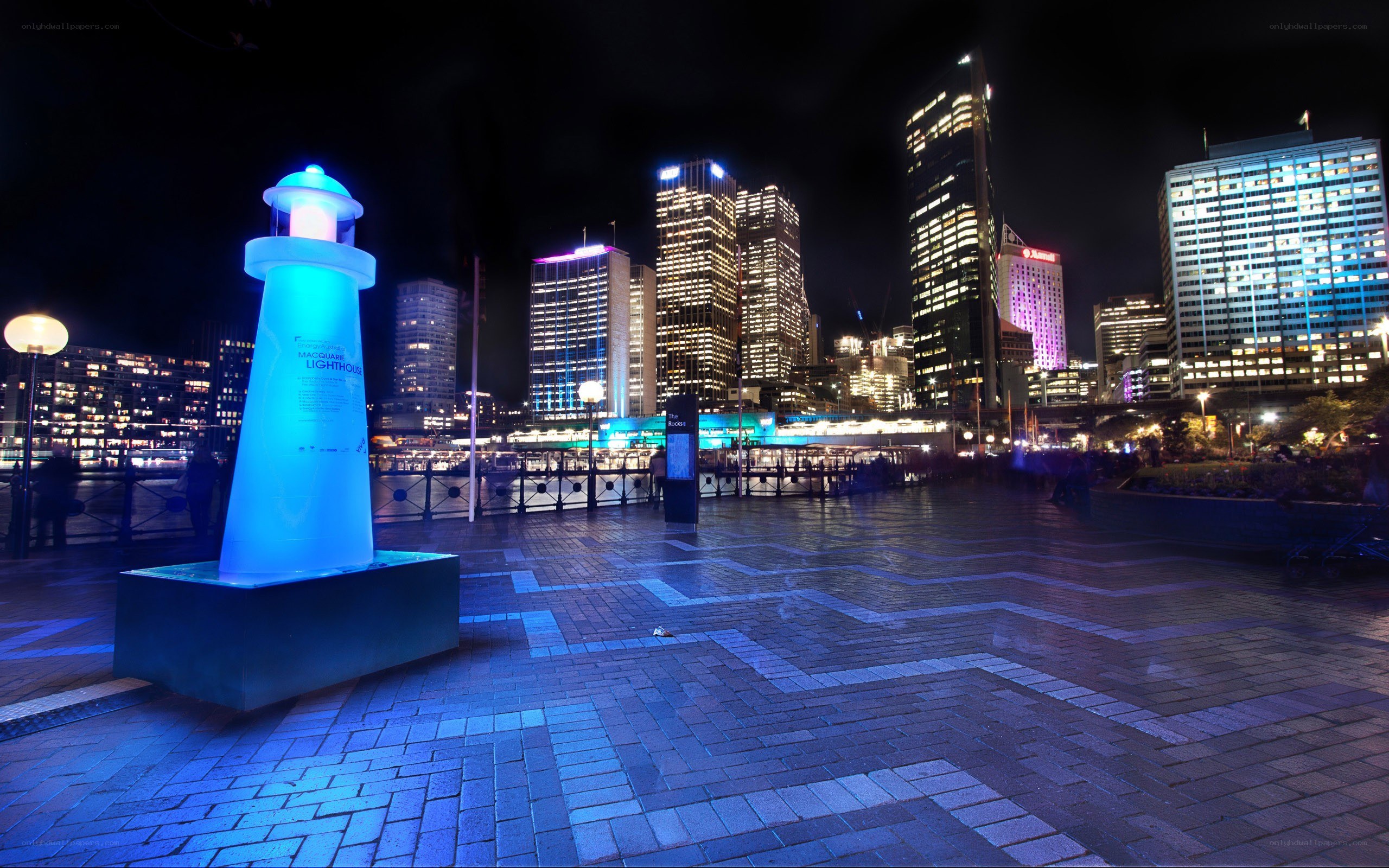 Nighttime cityscape with lighthouse sculpture