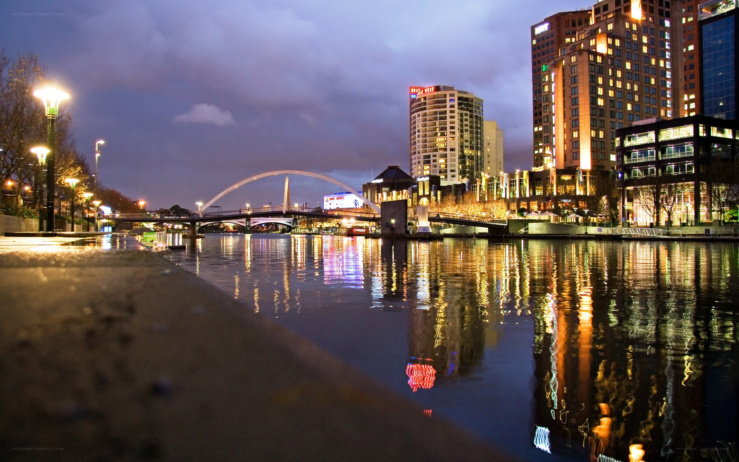 nighttime cityscape with river and bridge