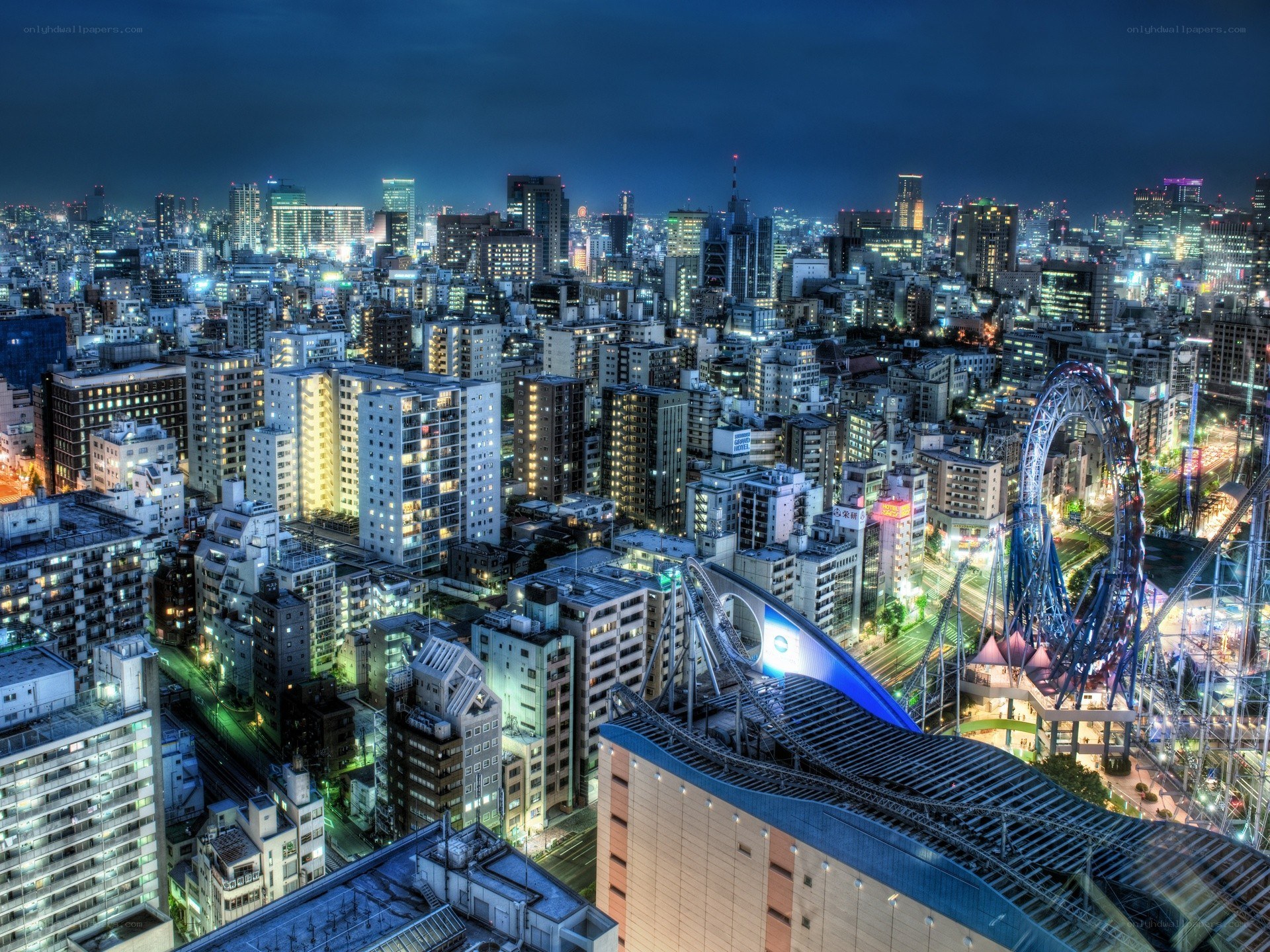 Nighttime cityscape with roller coaster