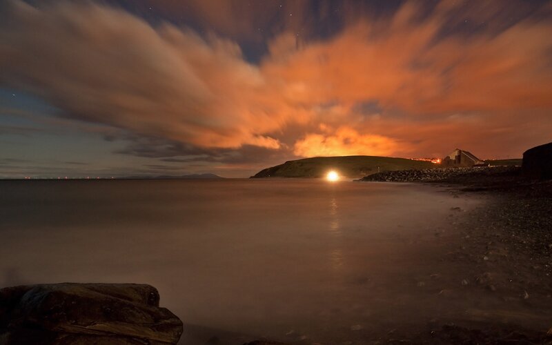 Nighttime coastal scene with glowing sky