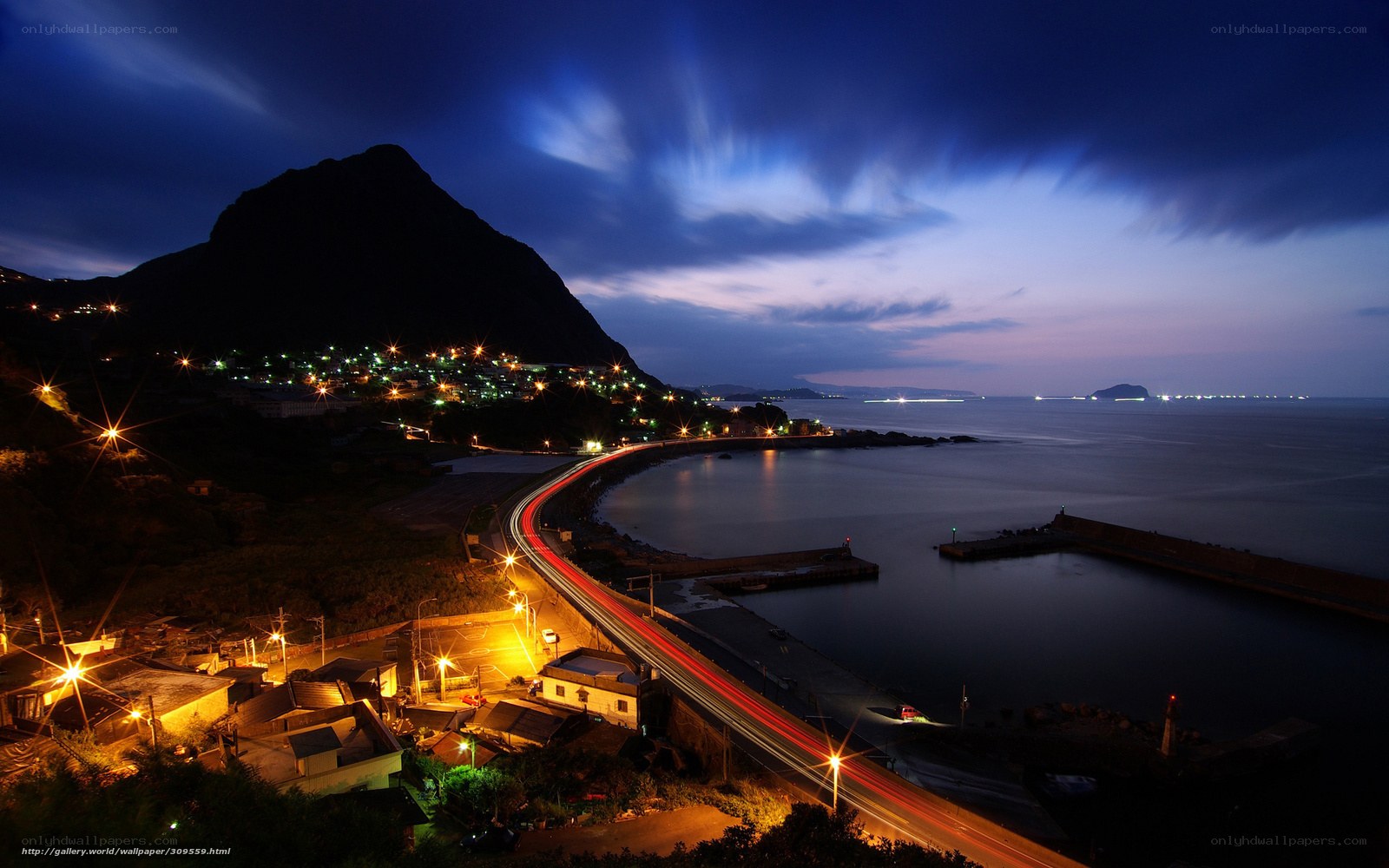Nighttime coastal town with light trails