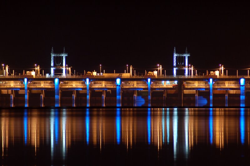 nighttime dam illuminated with blue lights