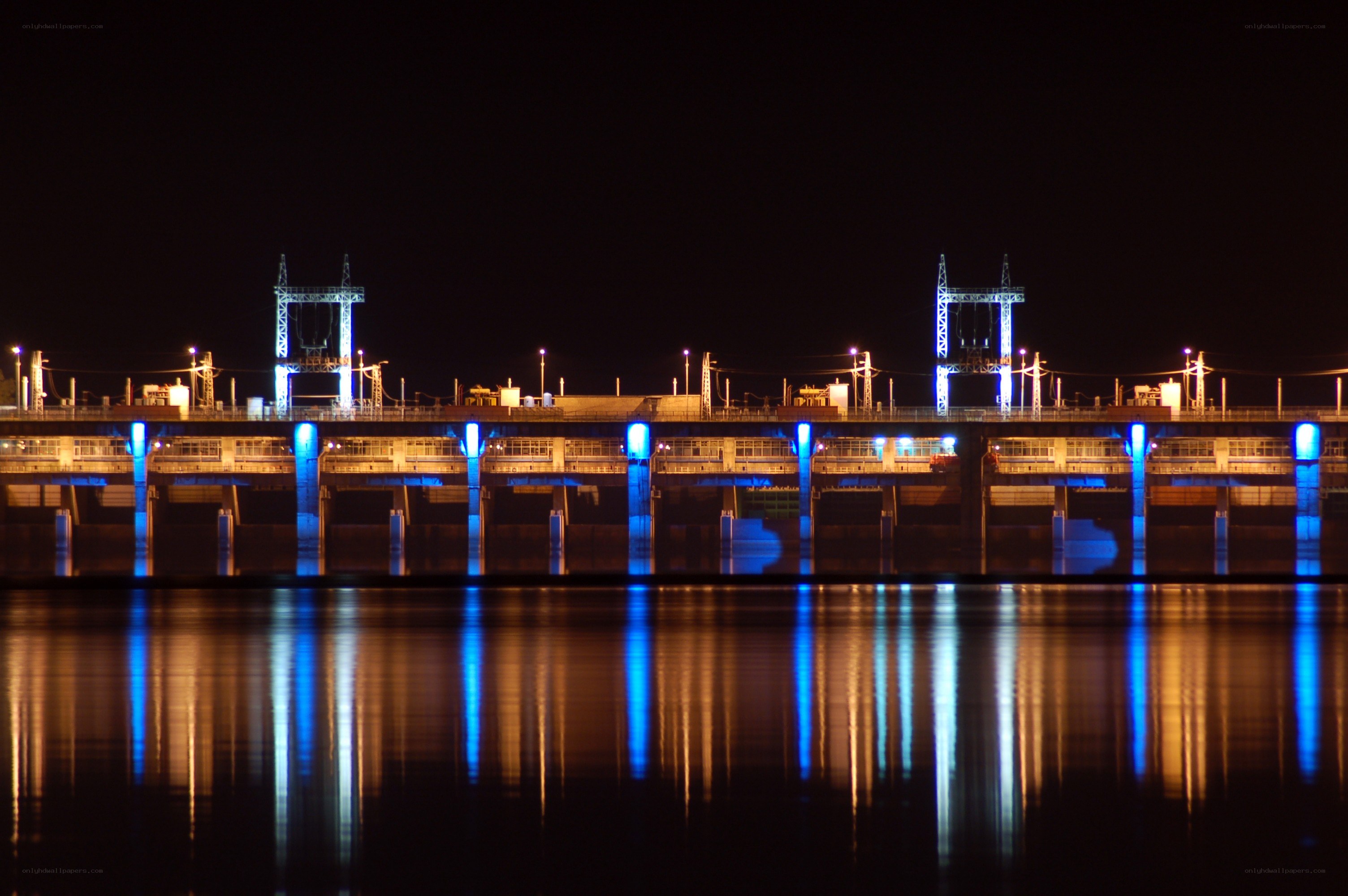 nighttime dam illuminated with blue lights