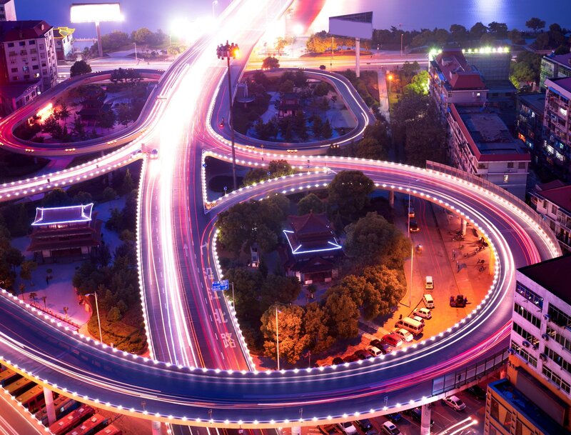 Nighttime highway interchange with light trails