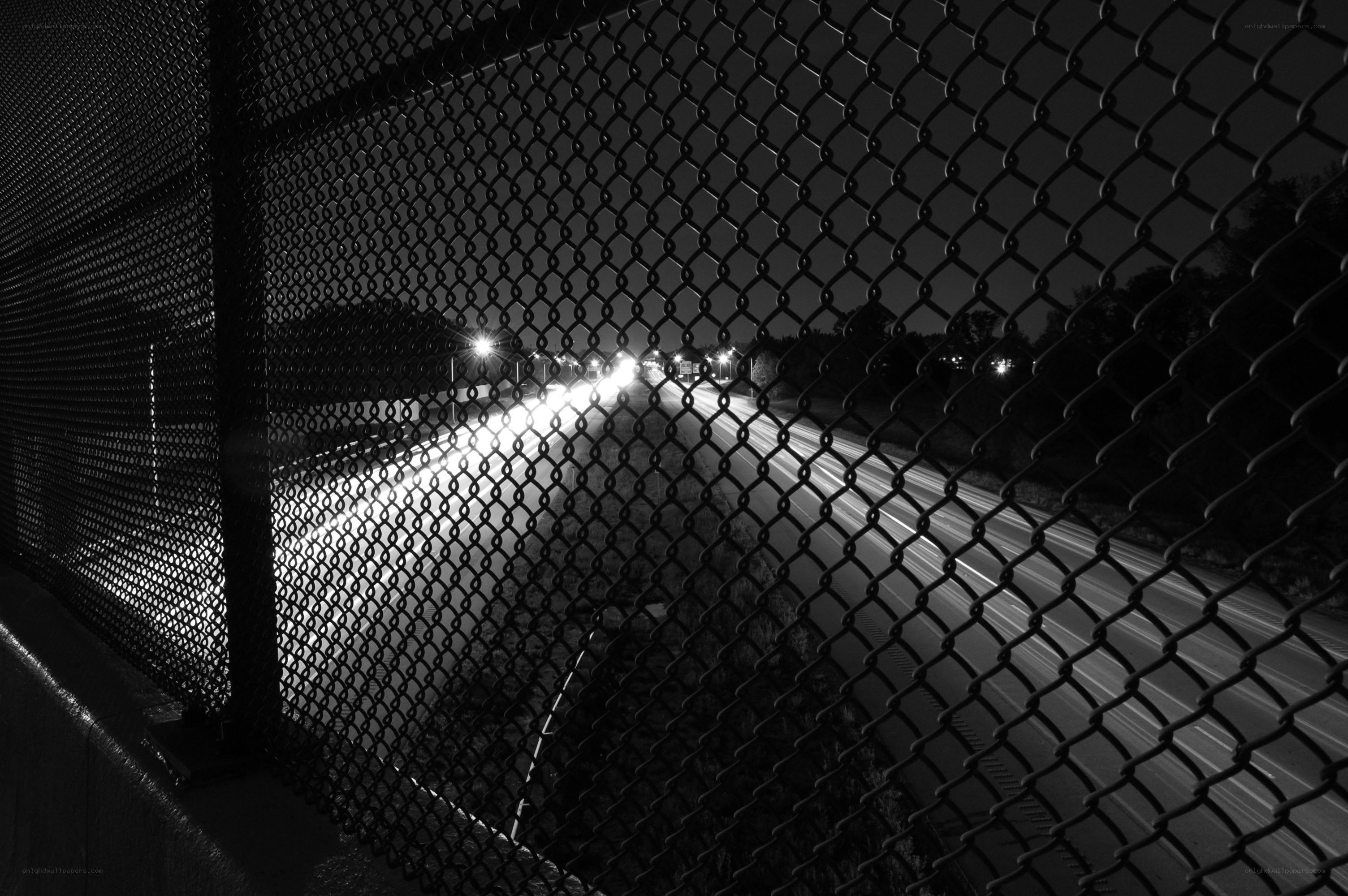 Nighttime highway through chain-link fence