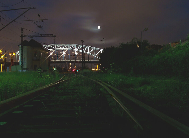 Nighttime railway tracks under a bridge