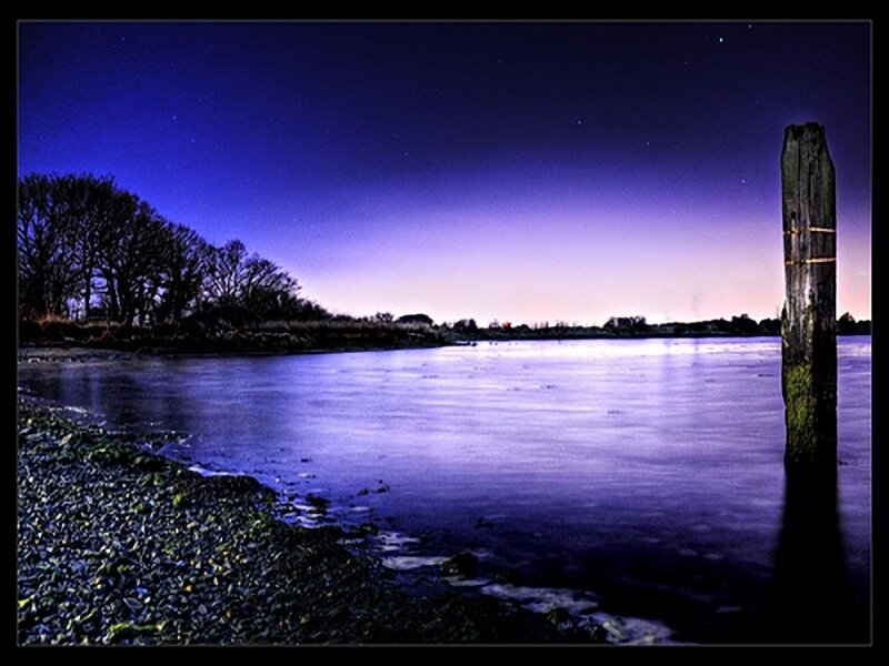 Nighttime river scene with wooden post