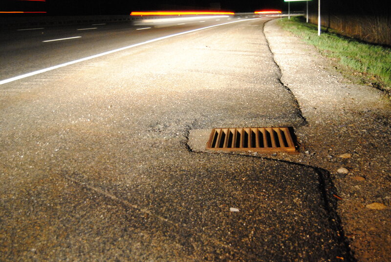 Nighttime road with drainage grate