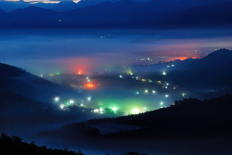 nighttime valley with fog and lights