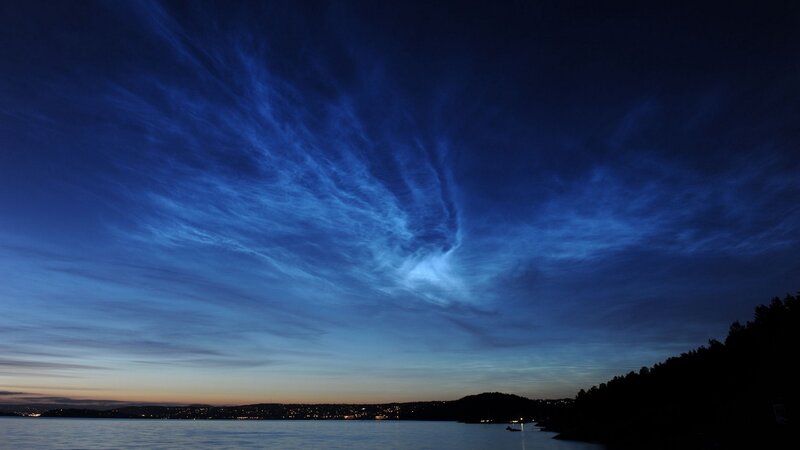 Noctilucent clouds over a coastal city