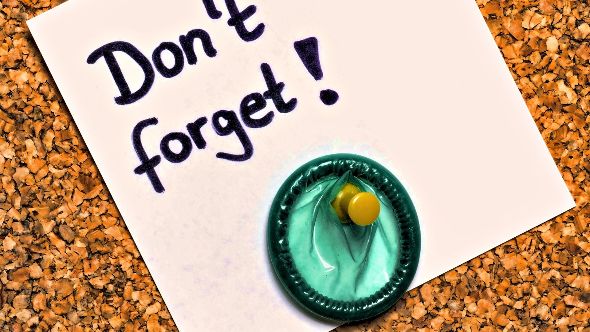 note with condom on corkboard
