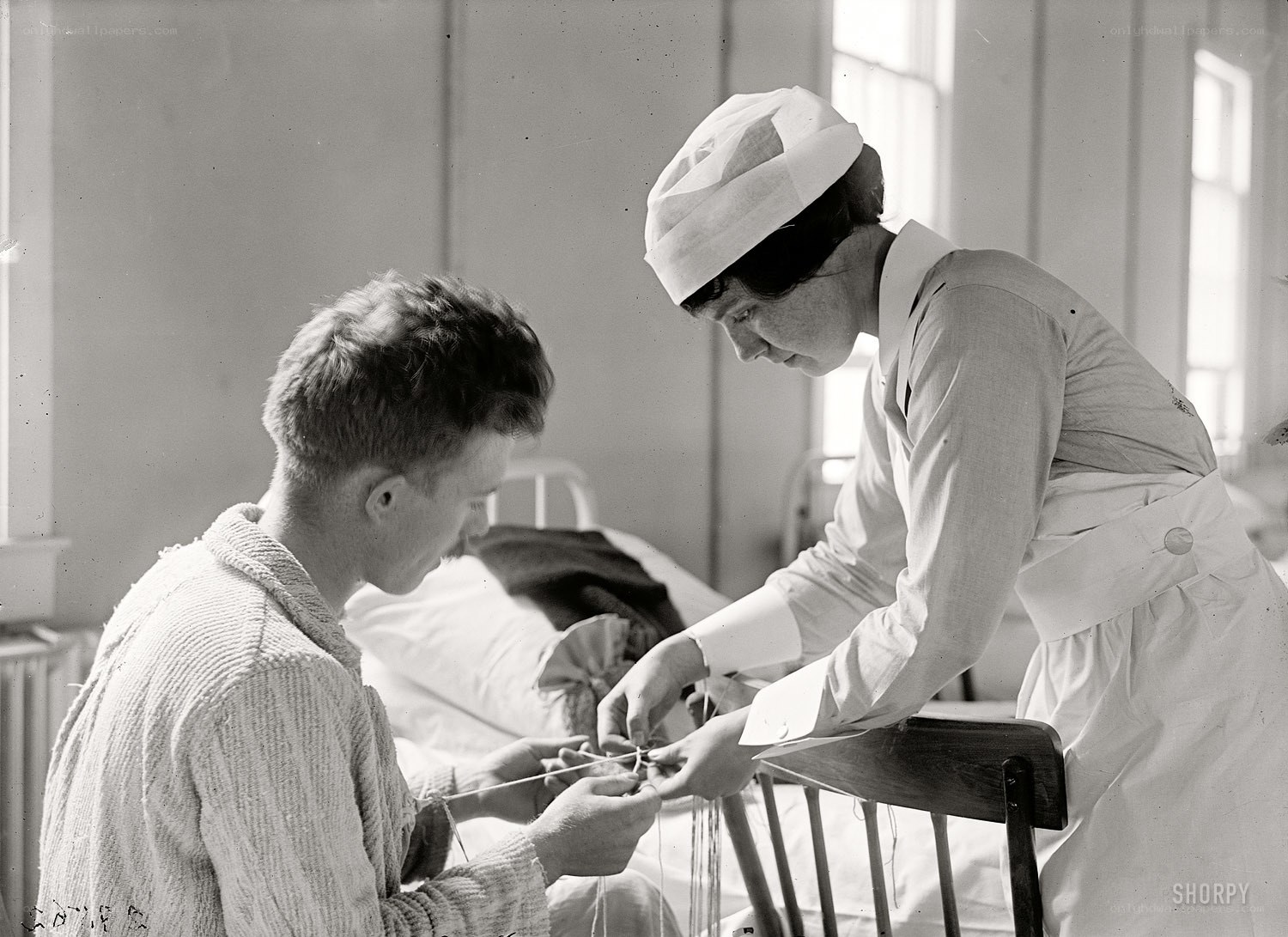 Nurse assisting patient with knitting