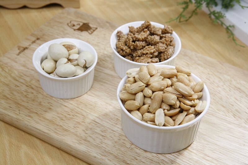 nuts in white bowls on wood