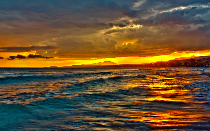Ocean Waves at Sunset — Orange, Dramatic, Photograph, Clouds, Mountains, Buildings