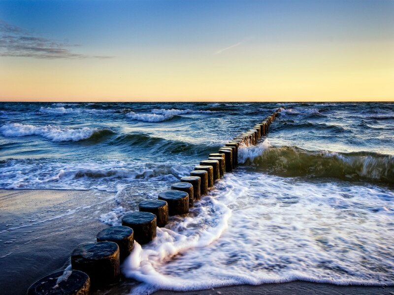 Ocean waves at sunset with groynes