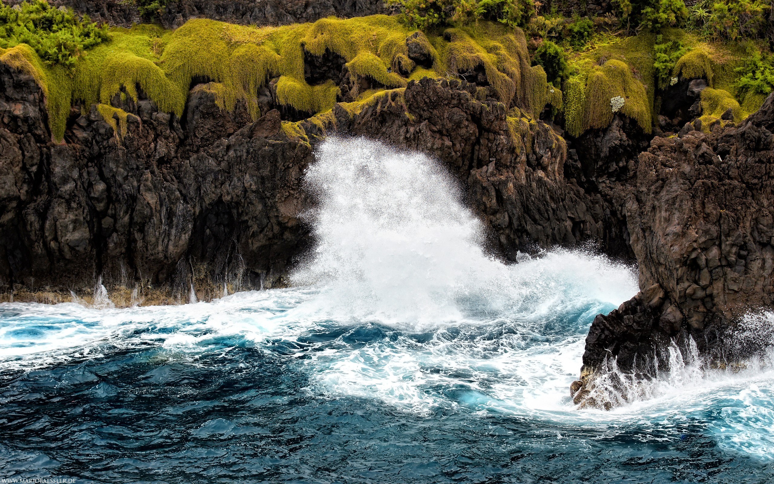 Ocean waves crashing on mossy cliffs