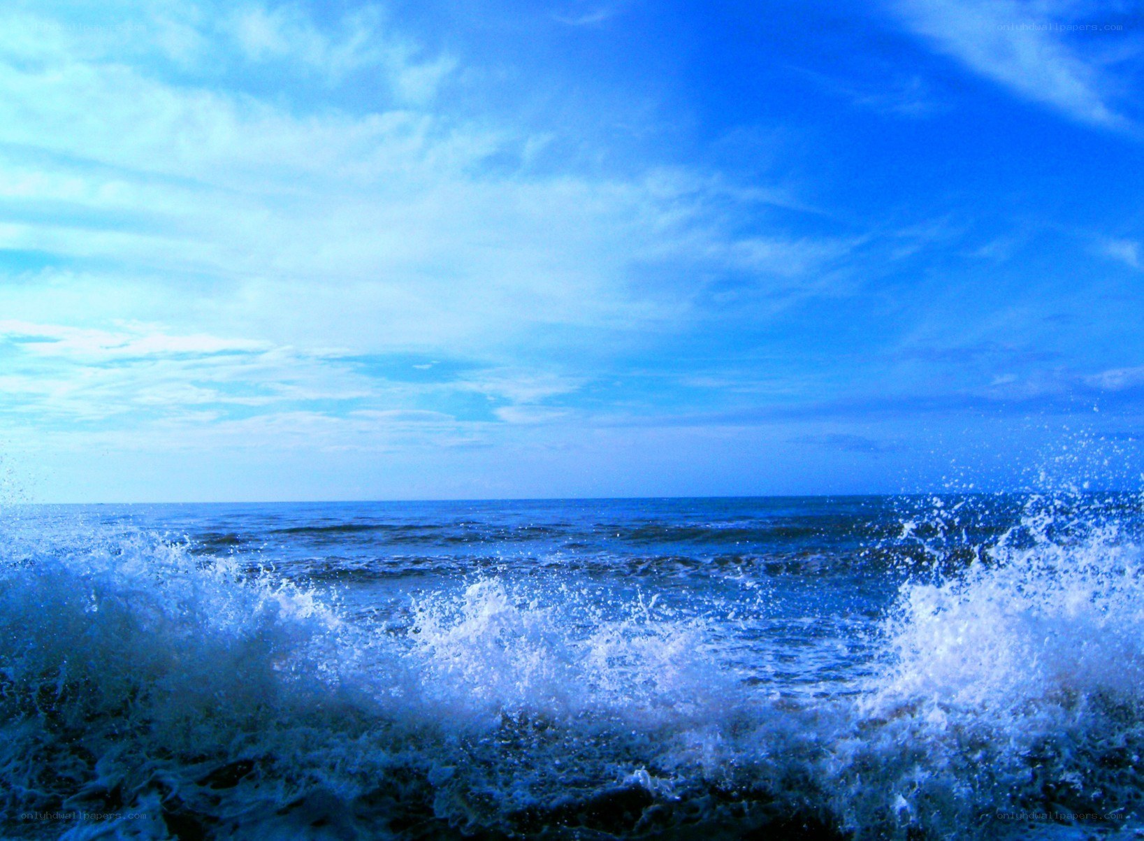 Ocean waves crashing under blue sky