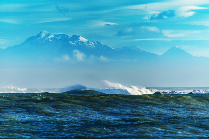 Ocean waves with snow-capped mountains
