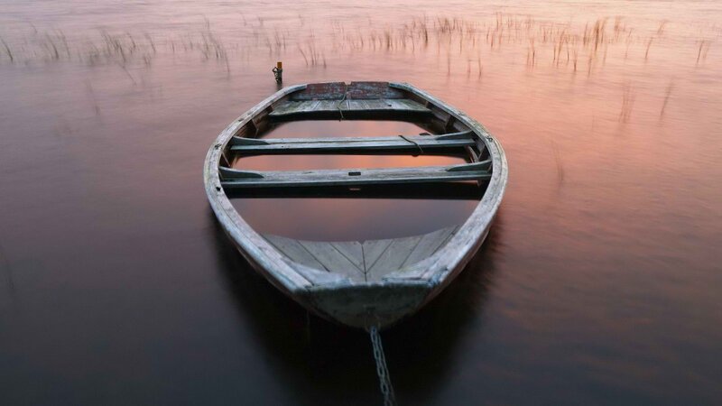 Old boat on calm water at dusk