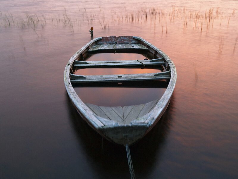 Old boat on calm water at sunset