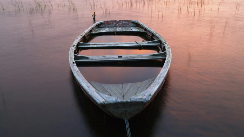 Old boat on calm water at sunset