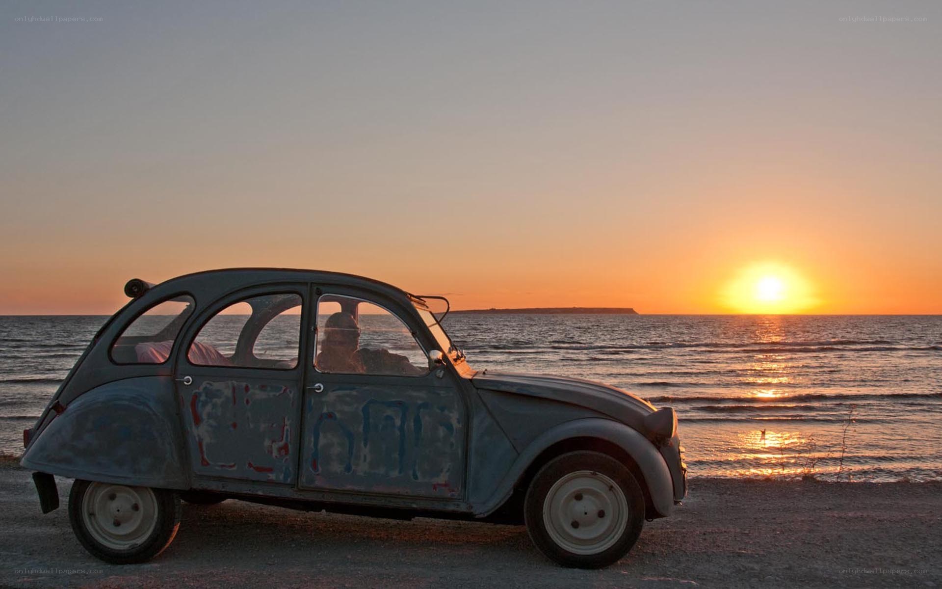 Old car on beach at sunset