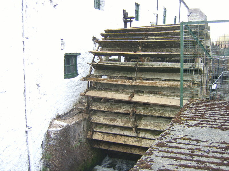 Old waterwheel by white building