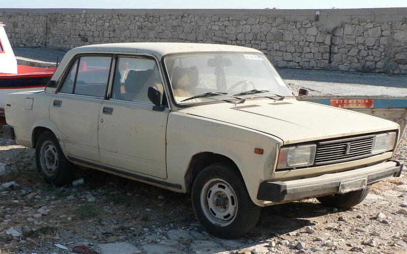 Old white sedan parked on gravel