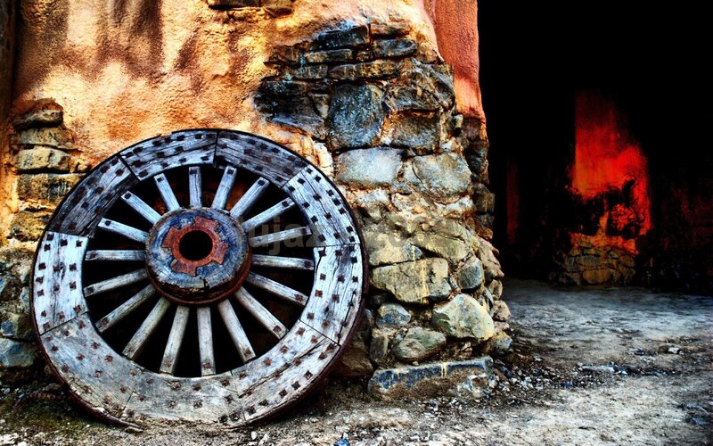 Old wooden wagon wheel against stone wall