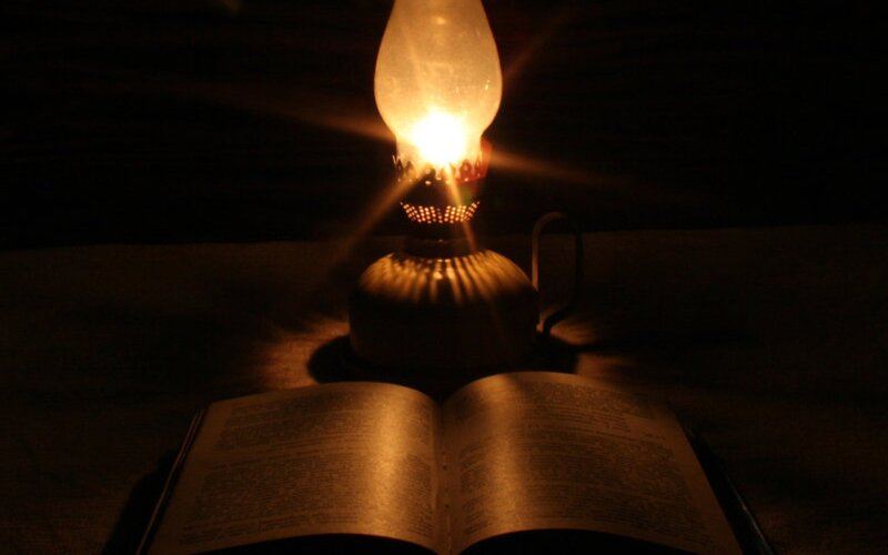 open book under oil lamp