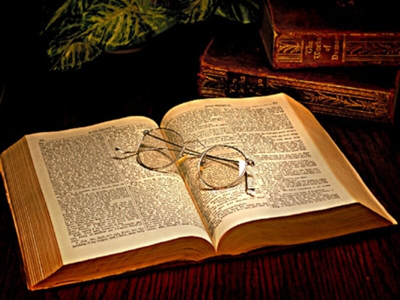 Open book with glasses on table