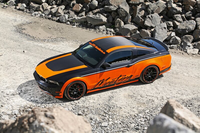 Orange and black Mustang on gravel