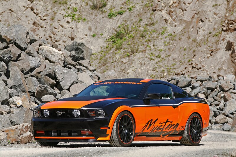 Orange and black Mustang on rocky terrain
