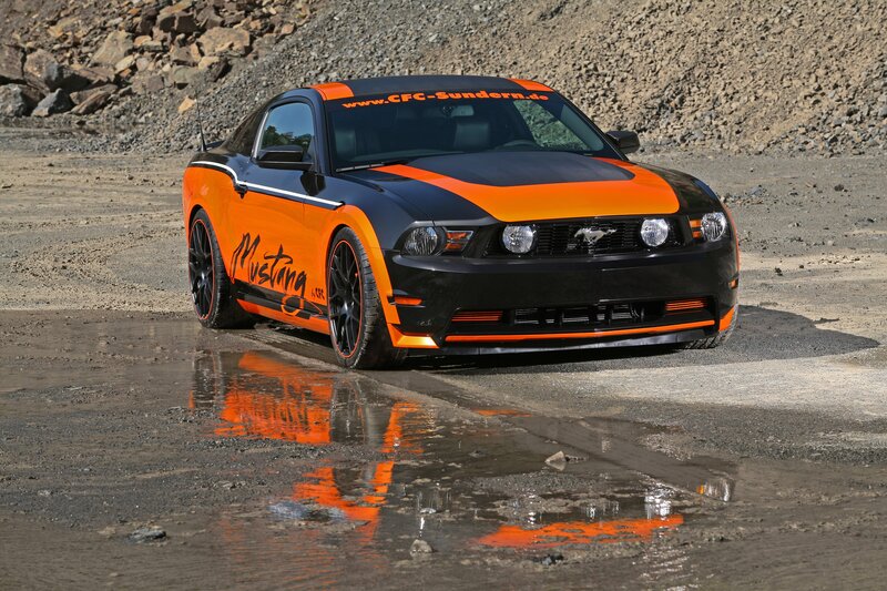 Orange and black Mustang on wet ground