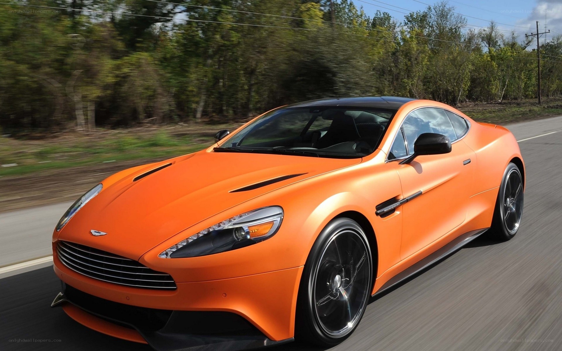 orange Aston Martin in motion