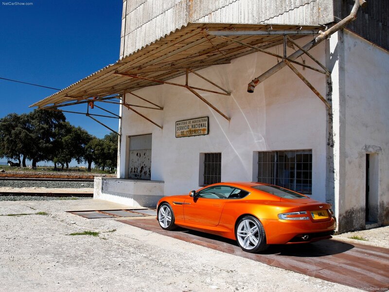 Orange Aston Martin parked by grain silo