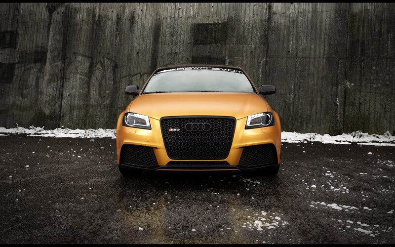 Orange Audi RS3 in front of concrete wall