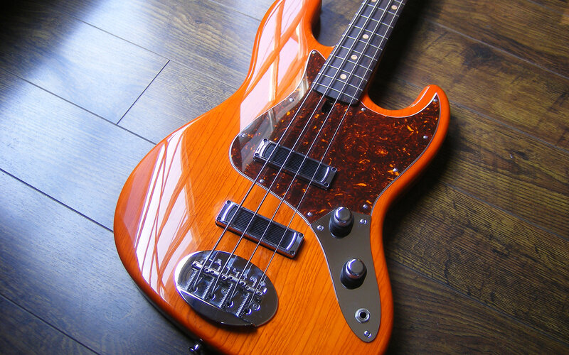 orange bass guitar on wood floor