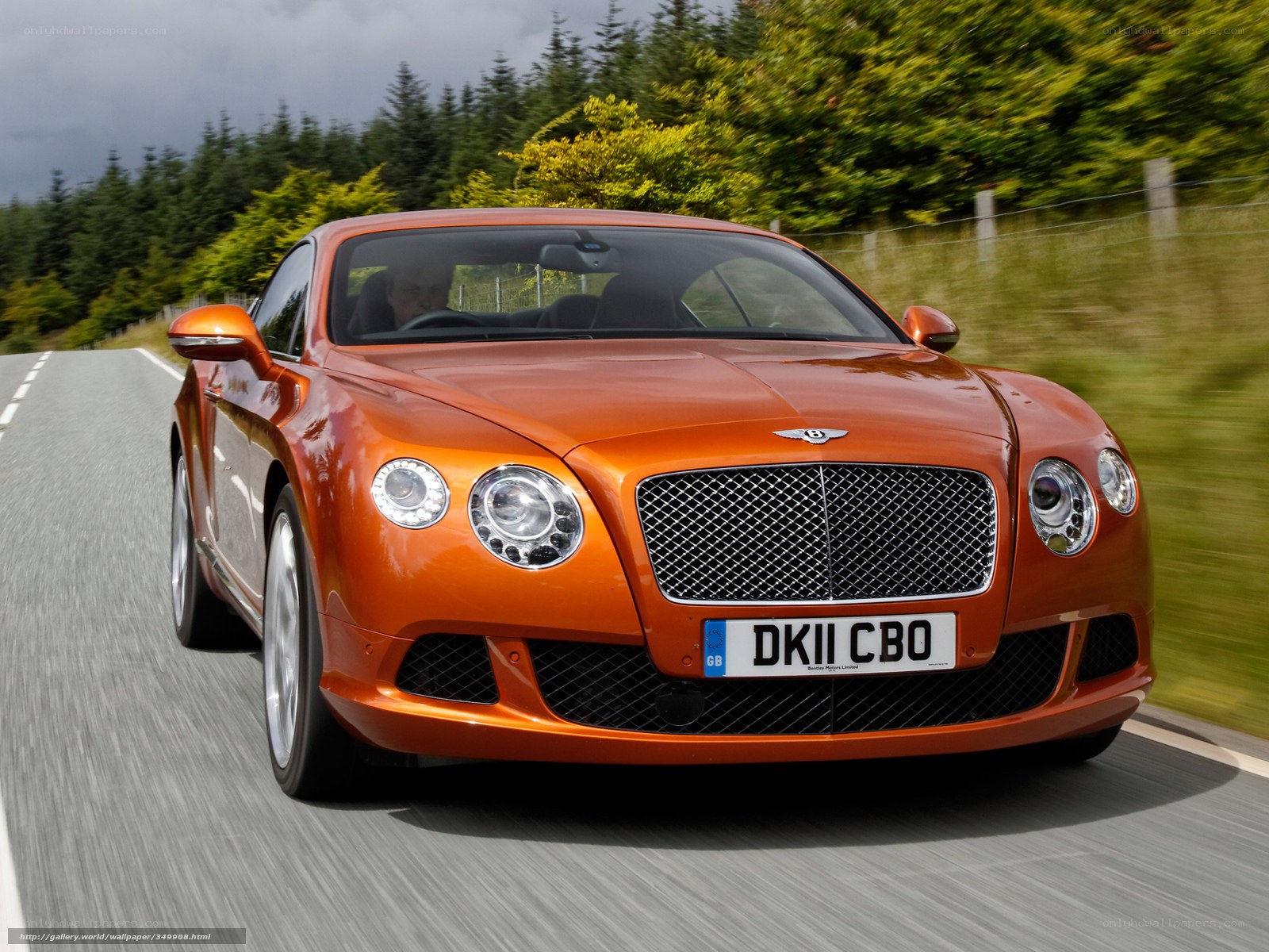 orange bentley driving on road