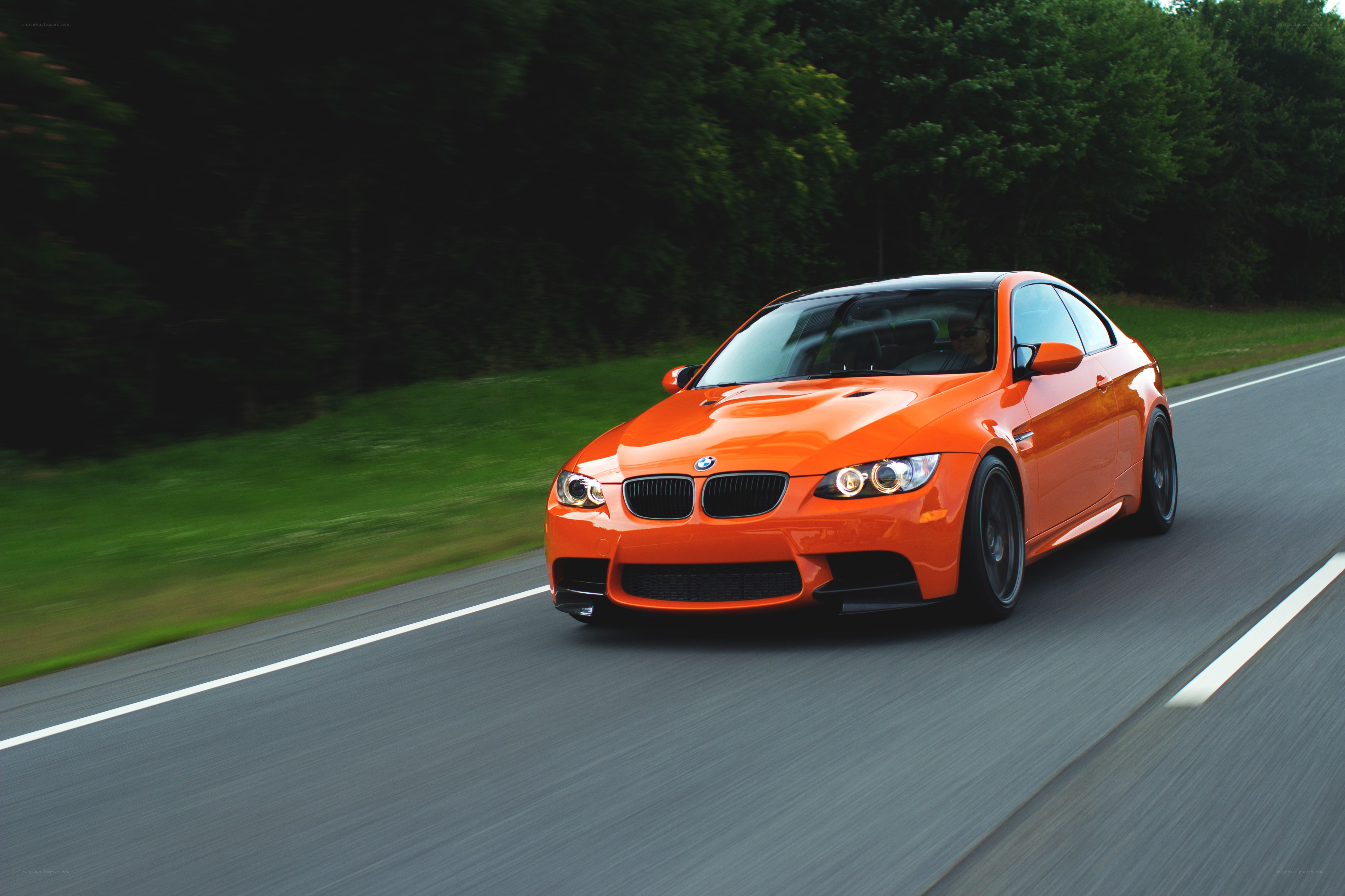 orange BMW driving on road
