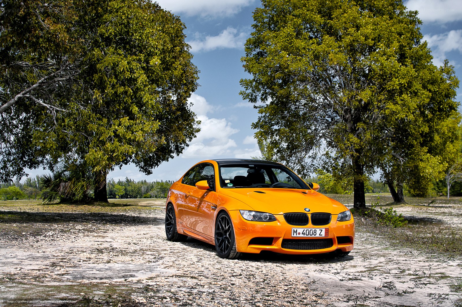 Orange BMW M3 on a gravel path
