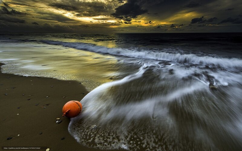 Orange buoy on beach at sunset