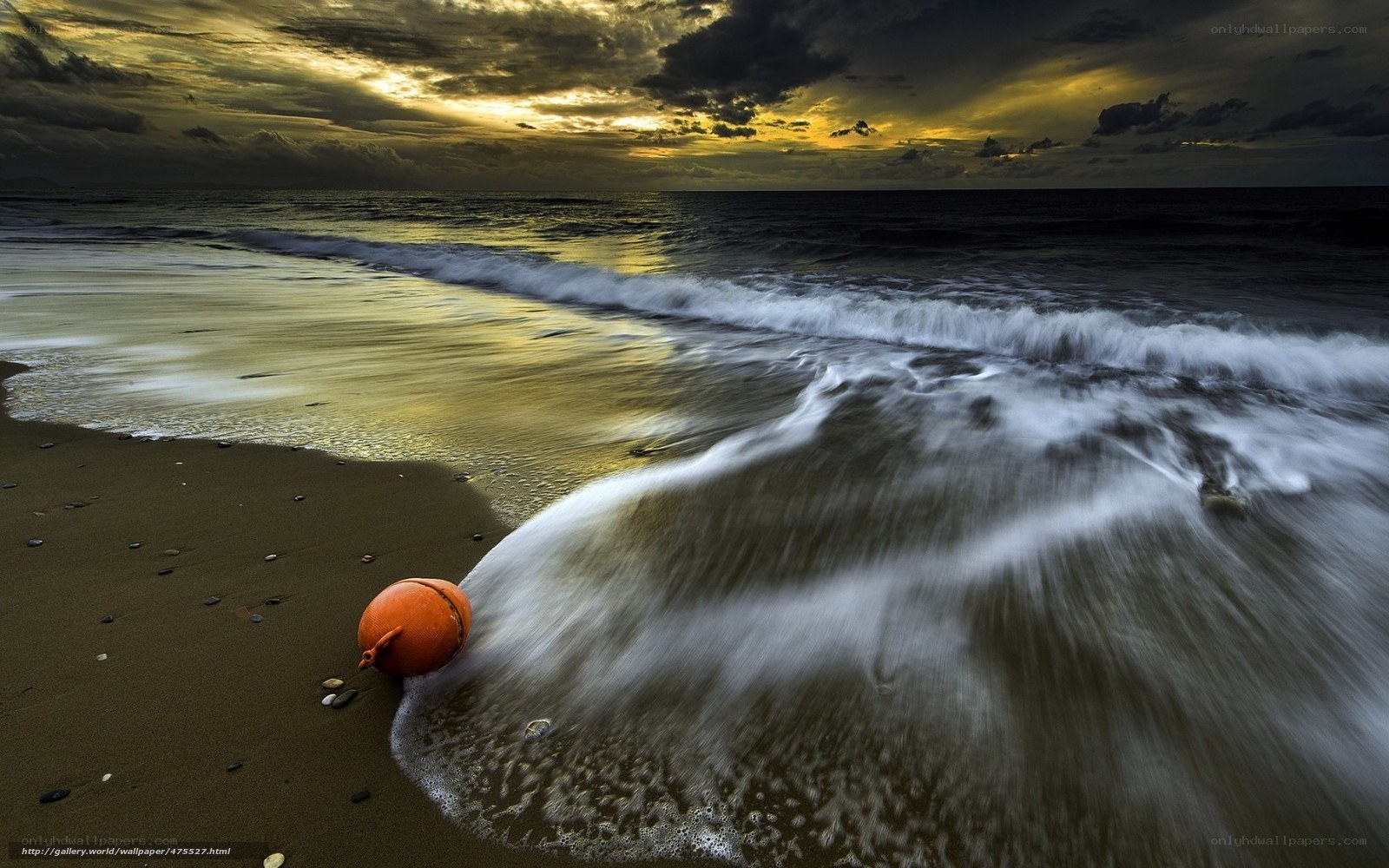 Orange buoy on beach at sunset