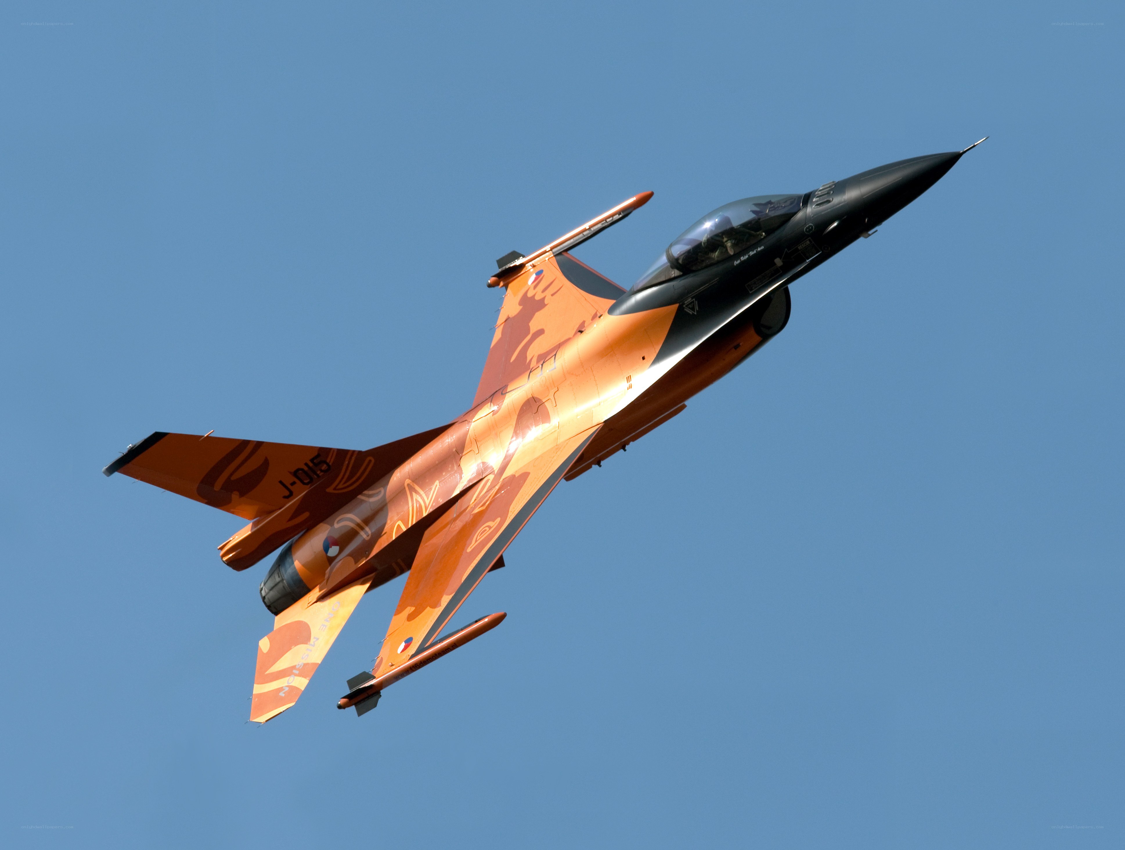 orange camo fighter jet in flight