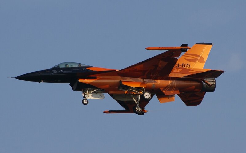 Orange camouflaged fighter jet in flight