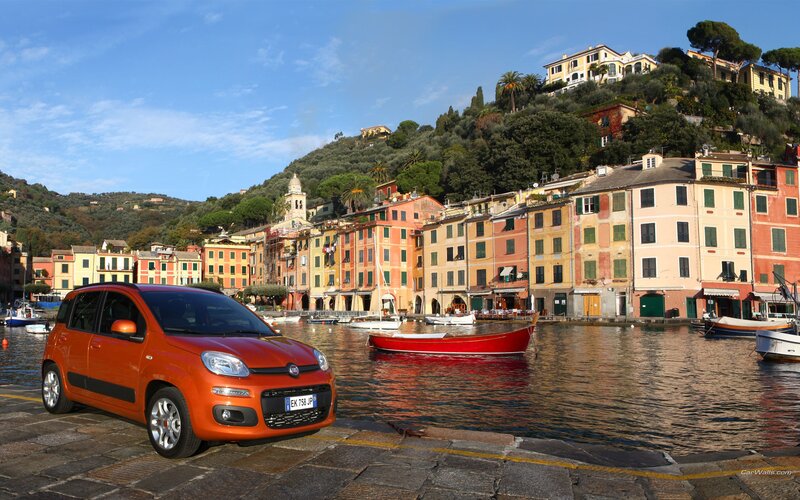 Orange car by a coastal village