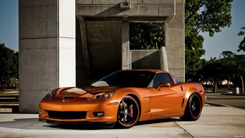 Orange Corvette parked under concrete structure