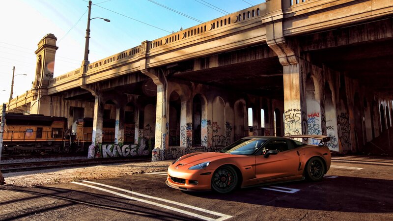 Orange Corvette under a bridge