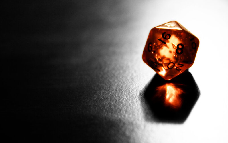 Orange d20 die on dark surface