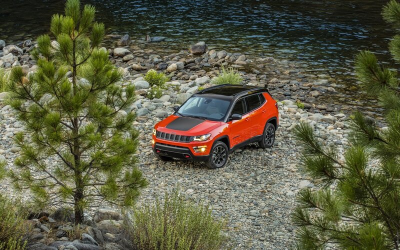 Orange Jeep on rocky riverbank